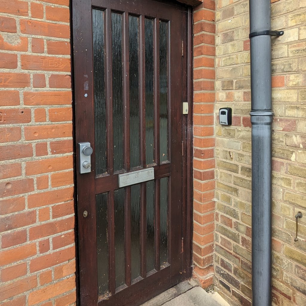The front door of the PMH with a key safe attached to the wall